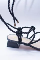 Sandalias doradas con tiras de cuerda para atar al tobillo.