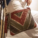 Bolso tipo sobre confeccionado en cuero de color terracota, verde y oro. Tiene una manija corta y una correa larga ajustable y removible. Su interior se encuentra forrado de tela gruesa.