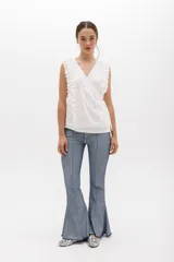 Musculosa cruzada de color beige, con escote en V y volados decorativos en los hombros y el frente.