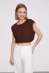 Chaleco corto de punto color marrón con ribete amarillo en cuello, sisas y bajo.