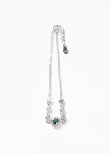 Pulsera de plata 925 con cadena de eslabones finos, decorada con zirconias circulares y un dije central en forma de corazón con una zirconia verde esmeralda rodeada de pequeñas piedras brillantes.