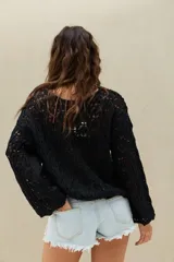 Sweater negro de punto con diseño calado, mangas largas y corte holgado.