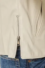Campera clásica de cuero ovino color beige claro, con cuello a la base, cierre frontal y bolsillos laterales con cierre. Presenta costuras verticales que estilizan la silueta.