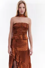 Top strapless de tela metálica con textura plisada, corte ajustado al cuerpo y diseño corto. Incluye una gargantilla a juego del mismo material.
