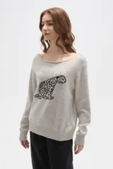 Sweater de tejido de punto color beige con estampado jacquard de leopardo en color negro. Presenta cuello redondo amplio y puños y ruedo acanalados.
