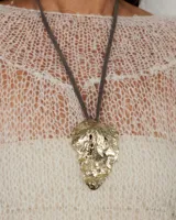 Gargantilla rígida de metal dorado con dije central de diseño orgánico y textura irregular. El diseño permite múltiples usos, incluyendo la opción de utilizar la gargantilla sola o con el dije.