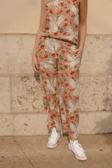 Pantalón de lino y algodón color beige con estampado de lobos blancos y labios rojos. Tiene elástico en la cintura y bolsillos laterales.