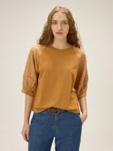 Remera de algodón con escote a la base y mangas raglán de broderie con costuras decorativas en color contrastante.