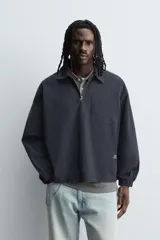 Camisa relaxed fit color azul marino, confeccionada en tejido de algodón con efecto lavado. Presenta cuello solapa, cierre frontal de cremallera, manga larga con puños elásticos y bolsillo de parche en el pecho. Incluye un pequeño estampado blanco en la parte inferior derecha.