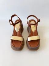 Sandalias de cuero con plataforma, color marrón con tira dorada sobre los dedos y tobillera marrón con hebilla.