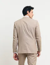 Ambo de dos piezas color tostado, compuesto por un saco entallado de dos botones y pantalón de vestir de corte recto.