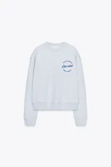 Sudadera de cuello redondo y manga larga, confeccionada en tejido gris melange. Presenta un diseño estampado en el pecho con un corazón y la frase 'Pasta fresca Ciao cara! Dell'Italia'. Cuenta con puños y ruedo acanalados.