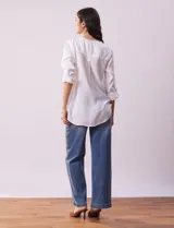 Blusa color beige de lino, marca Dash. Cuello a la base, escote en V y abertura con botones. Delantera con bolsillos. Largo de manga regulable con presilla y botón.