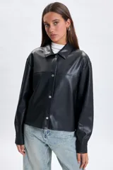 Sobrecamisa de cuero sintético en color negro, con cuello camisero, cierre frontal con botones metálicos a presión y mangas largas con puños abotonados.