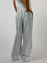 Pantalón largo de lino a rayas verticales en tonos beige, rosa y gris, con cintura alta y corte recto.