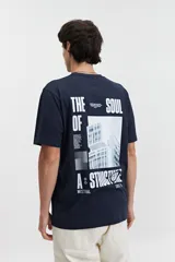 Remera azul marino de manga corta con cuello redondo y estampado de edificio moderno en la espalda.