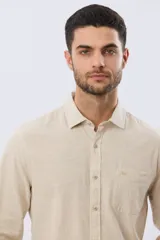 Camisa de lino de manga larga en color beige, con cuello camisero, cierre frontal de botones y un bolsillo ojal en el pecho.