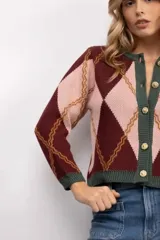 Cardigan de punto con patrón argyle en tonos gris y naranja, con cuello redondo, cierre frontal de botones dorados y bordes en color bordó.