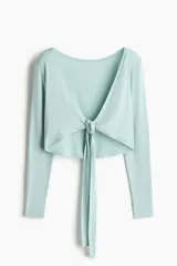 Top cropped de yoga color menta de manga larga, confeccionado en punto modal suave, con escote en V pronunciado y tiras para anudar al frente.