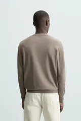 Jersey color crudo de tejido de punto, con cuello redondo y mangas largas. Corte amplio y terminaciones en rib.