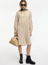 Vestido túnica color beige claro, con cuello mao, botones frontales y bordado en el pecho. Presenta tajos laterales.