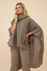 Poncho de lana fina sin teñir, con cuello alto tipo polera y detalle de cordones de cuero en el bolsillo frontal.