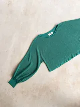 Buzo de tejido de punto con acabado brillante, confeccionado con hilado italiano. Presenta cuello redondo, mangas largas acampanadas y un corte holgado.