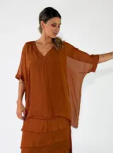 Blusa de viscosa color marrón chocolate, de corte holgado, cuello en V y mangas cortas amplias con vuelta.