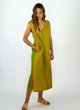 Vestido midi sin mangas, color verde oliva con detalles en verde más claro. Tiene escote en V, corte holgado, bolsillos laterales y aberturas en los costados de la falda.