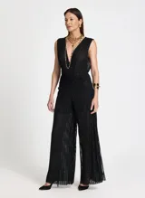 Pantalón de tiro alto con corte de pierna ancha y caída fluida. Confeccionado en tejido de punto con textura brillante y sutil transparencia, presenta una cinturilla ancha estructurada con un ligero fruncido bajo la misma y bajo recto.