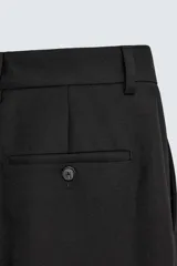 Pantalón de traje corte straight fit confeccionado en tejido mezcla de lana. Presenta cierre frontal con cremallera y botón, bolsillos laterales y bolsillos traseros de vivo.