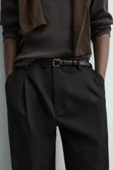 Pantalón straight fit color negro confeccionado en tejido con lana, con detalle de pliegues en el delantero, bolsillos frontales y traseros, y cierre frontal con cremallera y botón.