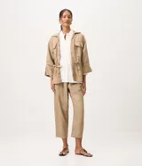 Campera tipo parka de la marca Marfinno, confeccionada en mezcla de algodón, viscosa y lino en color beige. Presenta cuello camisero, cierre frontal con botones, bolsillos con solapa en el pecho y cintura ajustable con cordón y lazo. Las mangas son largas con puños abotonados.