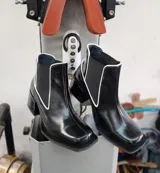 Bota tipo chelsea de cuero negro con detalles de costuras en blanco, puntera cuadrada y taco bloque.