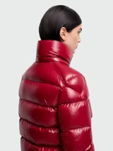 Campera puffer de nylon brillante en color rojo, con capucha desmontable, cierre frontal y bolsillos laterales. Presenta un diseño acolchado horizontal y logo de la marca en la manga.