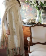 Chal de lana merino de gran tamaño, con diseño de texturas, rombos y calados, terminado con largos flecos multicolor.