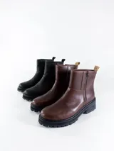 Bota corta negra de cuero con cierre lateral dorado, suela track y plataforma baja.