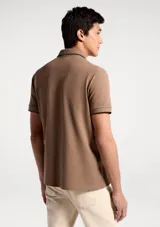 Remera polo blanca de manga corta, con cuello camisero y ribetes grises en cuello y puños. Cuenta con cierre frontal de botones y un pequeño logo bordado en el pecho.