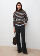 Sweater de punto con diseño de rayas horizontales en tonos marrón y celeste, cuello alto y manga larga. Presenta un corte oversize y acabado suave.