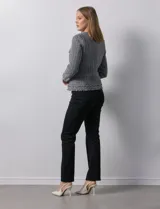 Chaqueta Nanette de tejido tweed color beige, con cuello a la base, abertura central y bolsillos delanteros. Tiene apliques de botones perlados en los puños, terminación desflecada y forro interno.