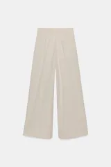 Pantalón de tiro medio color marrón, con pinzas en el delantero, perneras anchas de corte recto y trabillas para cinturón. Cuenta con bolsillos laterales y traseros, y cierre frontal con cremallera y botón.