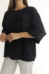 Sweater color beige de tejido de punto, con cuello redondo, manga larga con botón decorativo y bolsillo de parche en el pecho.