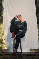 Crewneck (jersey de cuello redondo) unisex color gris oscuro, con estampado frontal que dice "RE:SKIN" y texto pequeño debajo. Presenta mangas largas y corte holgado.