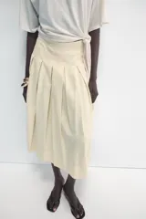 Falda midi de tiro medio ZARA Woman Collection confeccionada en hilatura con lino, con detalle de pliegues, bajo acabado en línea evasé y cierre lateral con cremallera oculta en costura.