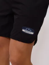 Short de baño tipo volley color verde azulado, con cintura elástica y cordón de ajuste en color azul marino. Presenta un parche con el logo de la marca en la pierna izquierda y aberturas laterales en el ruedo.