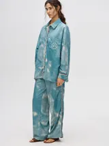 Pantalón de tiro alto con corte recto y holgado, confeccionado en tela liviana con estampado tipo tie-dye en tonos azul y blanco.