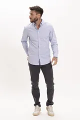 Camisa de vestir de corte entallado, color celeste con microestampado de rayas verticales, cuello clásico y mangas largas con puños abotonados.