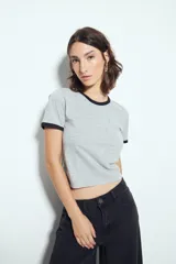 Remera cropped gris melange de manga corta, con cuello redondo y terminaciones en contraste de color negro, inspirada en los clásicos de los años 80.