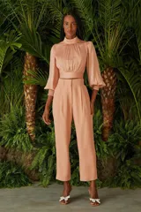 Blusa color beige con cuello alto fruncido, mangas largas abullonadas con puños elásticos y corte crop.