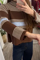 Sweater tejido de punto corto, con cuello redondo y diseño a rayas horizontales en tonos marrón, blanco y celeste.